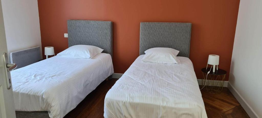 two beds in a room with orange walls at Résidence Auger in Bourges