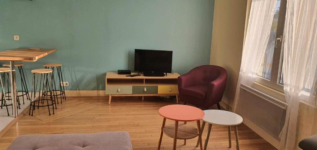 a living room with a tv and some chairs and a table at Résidence Auger in Bourges