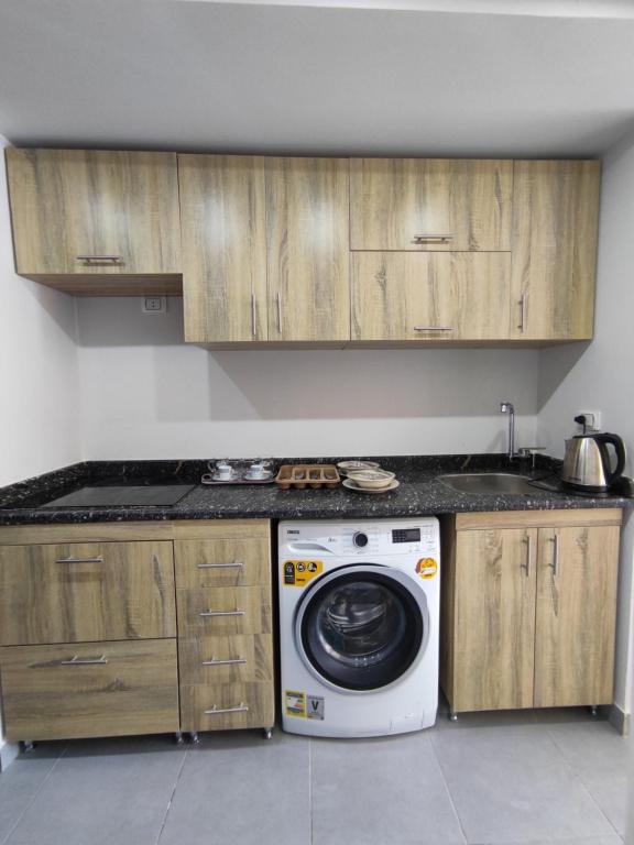 a kitchen with a washing machine and wooden cabinets at You are welcome to Mido Shallet in Naqādah