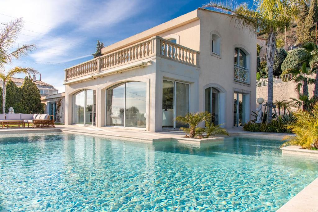 a villa with a swimming pool in front of a house at Beautiful Villa with amazing Monte Carlo & Sea View in La Turbie