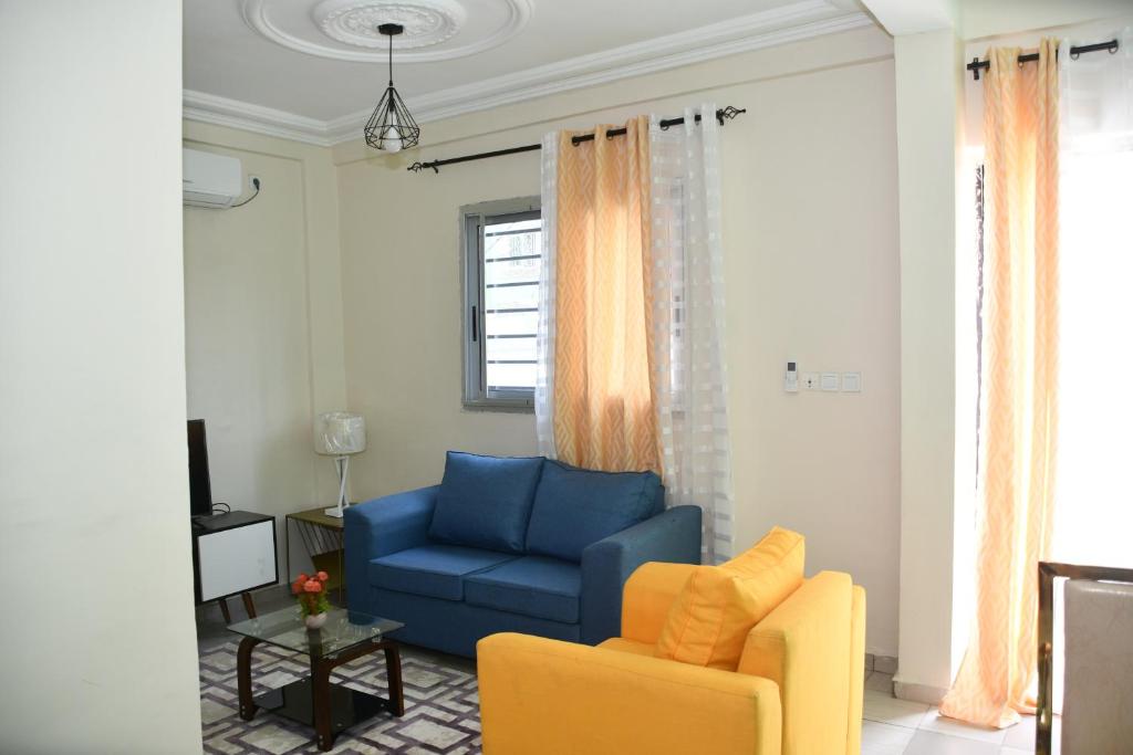 sala de estar con sofá azul y silla amarilla en Spetiv Guesthouse, en Douala