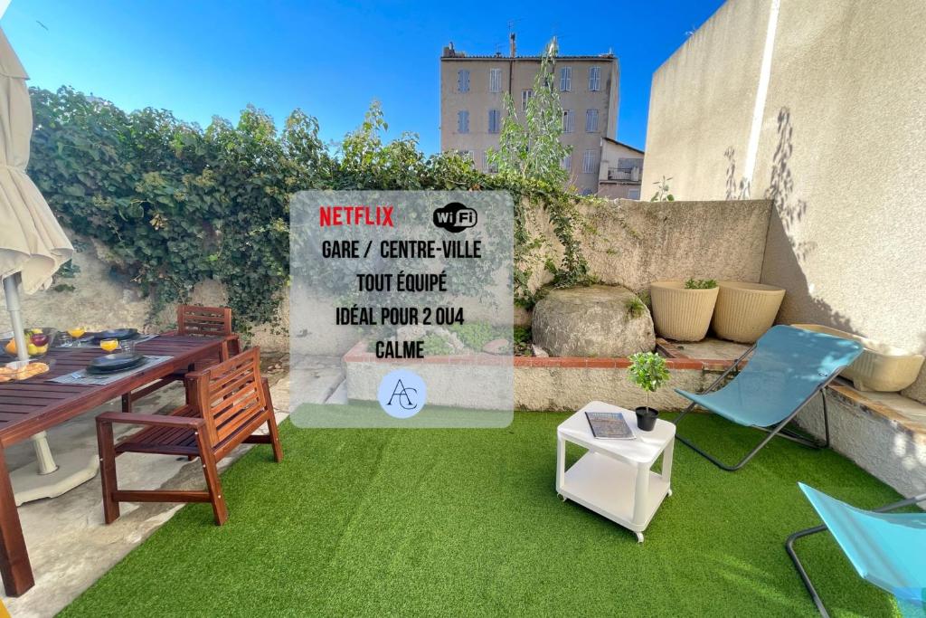 d'une terrasse avec de la pelouse verte, une table et des chaises. dans l'établissement Le Grand Bleu TerrasseClimWifiNetflix Proche Gare-Centre, à Marseille