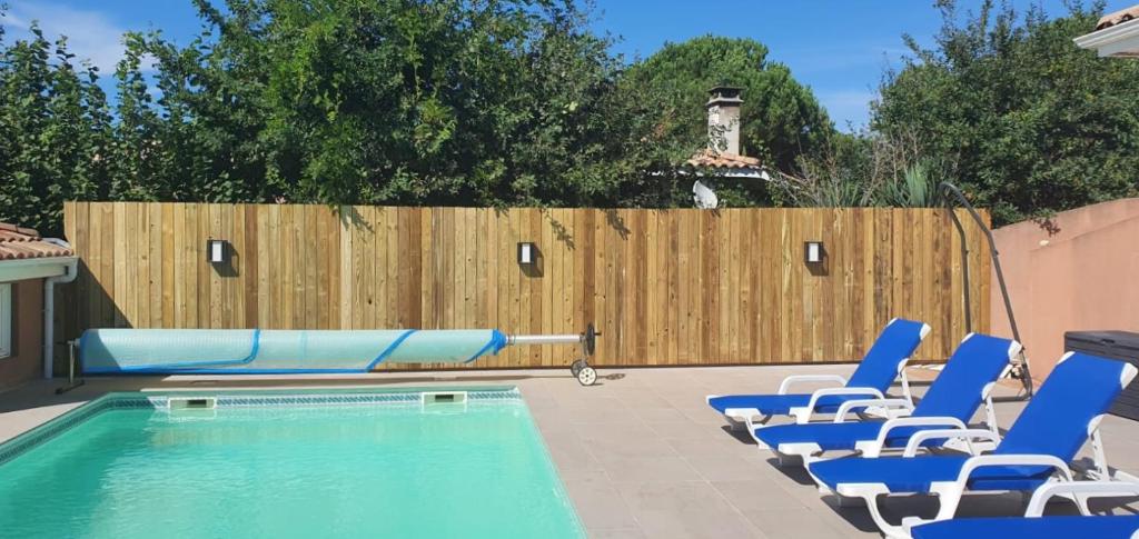 une piscine avec des chaises longues bleues et une clôture dans l'établissement Bassin d'Arcachon belle villa moderne 4 chambres et piscine privée, à La Teste-de-Buch