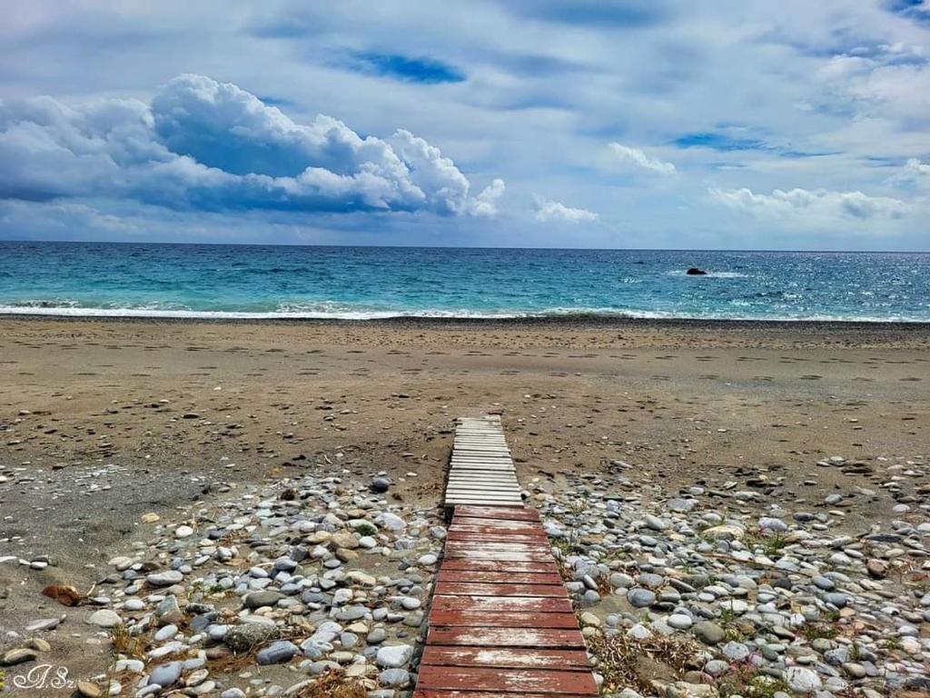 a wooden pathway on a beach with the ocean at Livikon Studios & Rooms in Rodakino