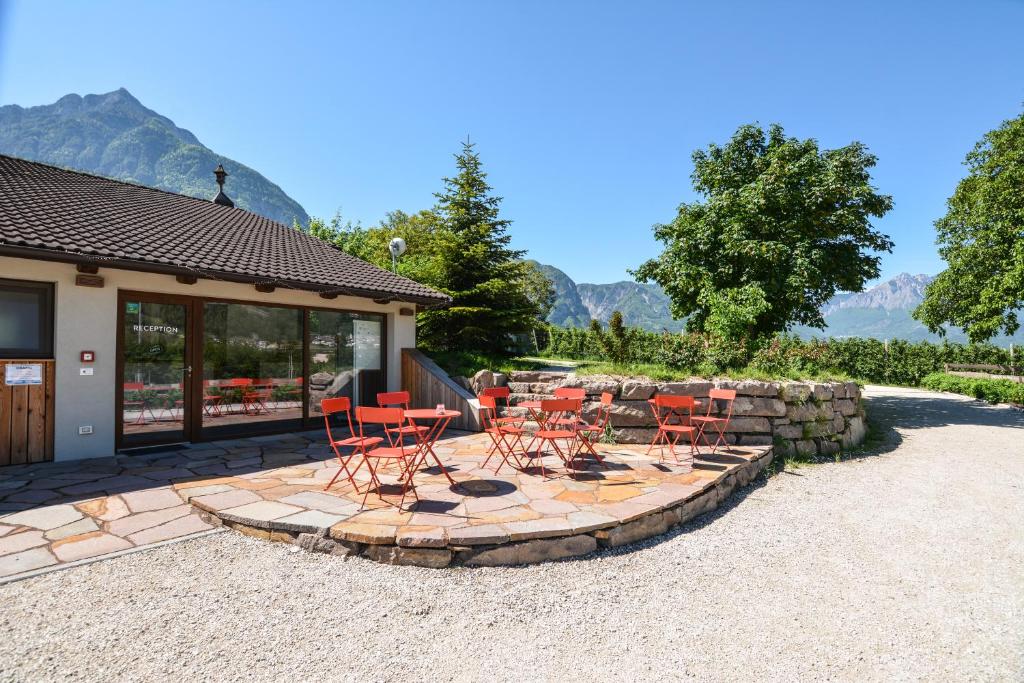 レーヴィコ・テルメにあるAgritur Airone Bed & Campingの赤い椅子とテーブルが並ぶパティオ