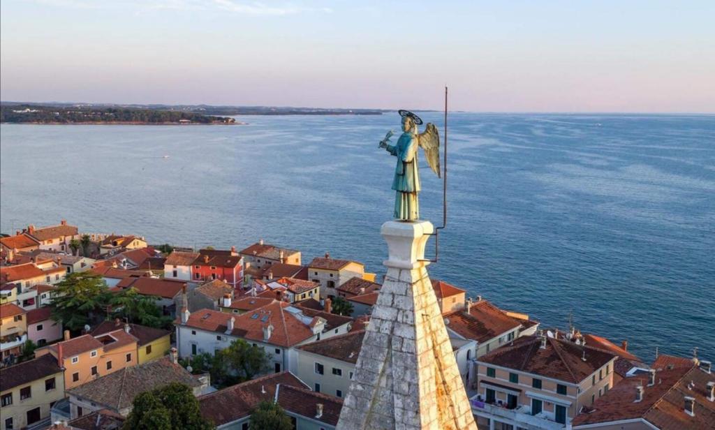 Una estatua de un ángel de pie en la cima de una ciudad. en Alina centar, en Novigrad Istria