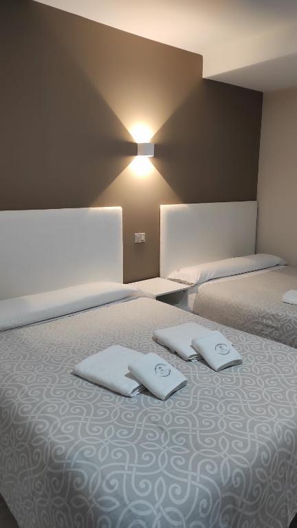 um quarto com 2 camas e toalhas brancas em Pensión NAVIA A Pontenova em A Pontenova