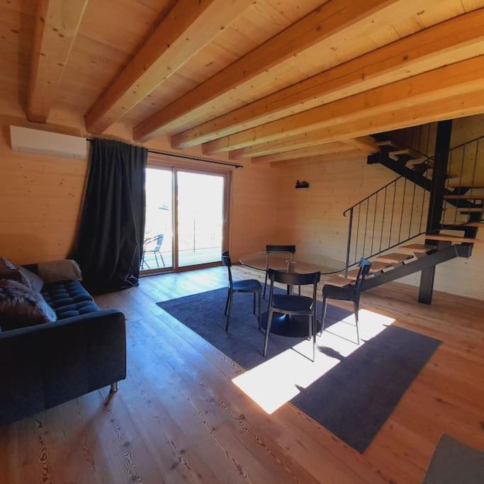 - un salon avec une table et des chaises ainsi qu'un escalier dans l'établissement Chalet Ridente con Patio al Gufo, à Ovaro