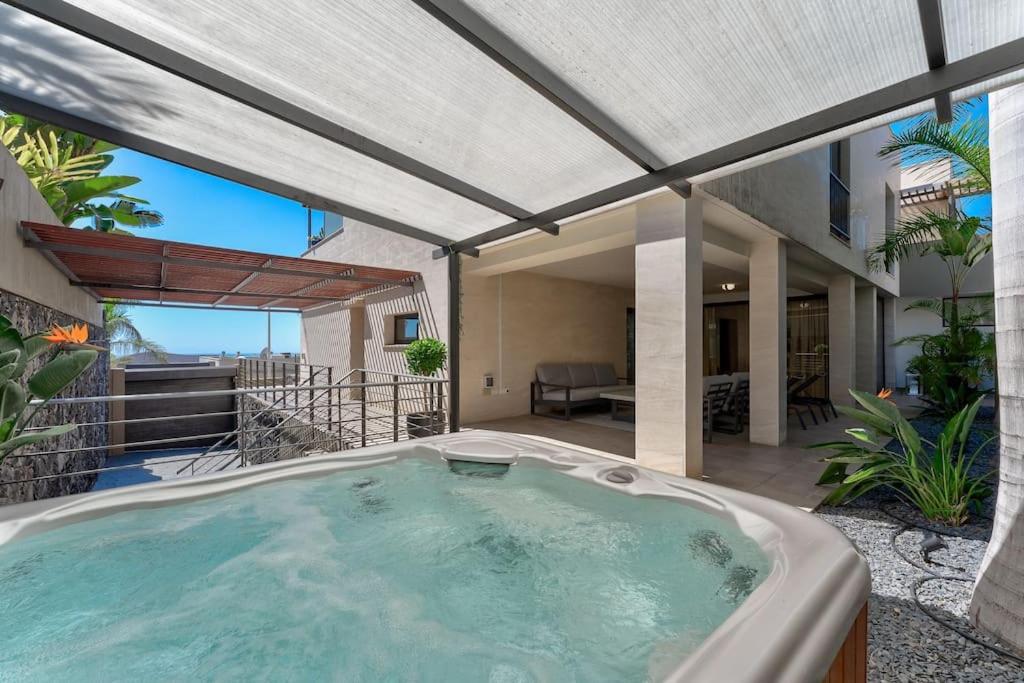 un bain à remous sur une terrasse avec une maison dans l'établissement Tajinaste villa, à Adeje