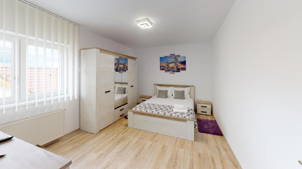 a bedroom with a bed and a large window at Harmony Apartment VRT in Şelimbăr
