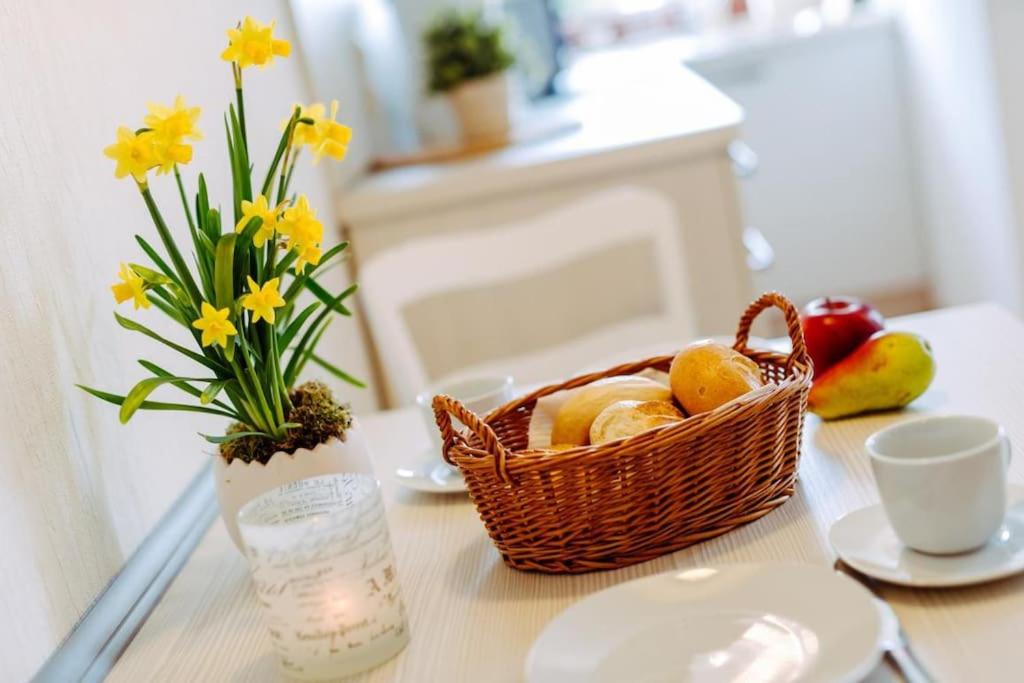 een tafel met een fruitmand en een vaas met bloemen bij Das Harznest, WLAN in Bad Sachsa