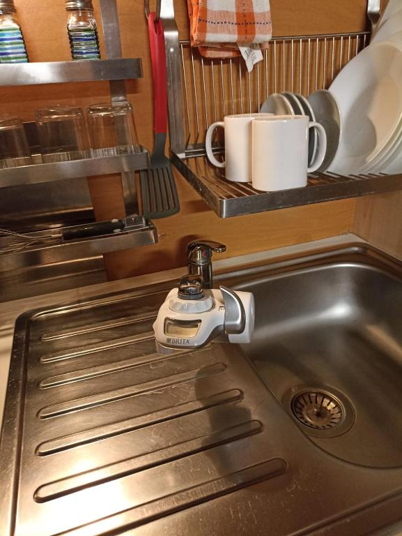 zlew kuchenny z kranem i kubkami na półce w obiekcie Al Mare In Città w Katanii