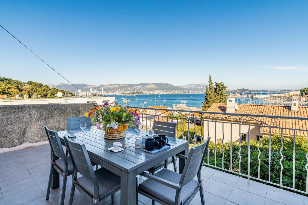une table et des chaises sur un balcon avec vue sur l'eau dans l'établissement Superbe appartement 2 chambres en haut de Villa, à Saint-Mandrier-sur-Mer