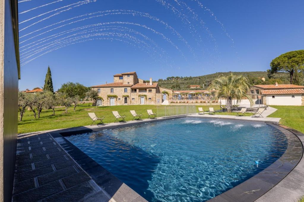 uma piscina com cadeiras e uma casa ao fundo em Nello's, Villa di pregio con SPA em Cortona