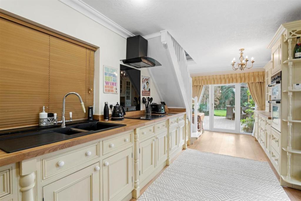 a large kitchen with white cabinets and a sink at The Corner House, 36, Broadway Road, in Evesham