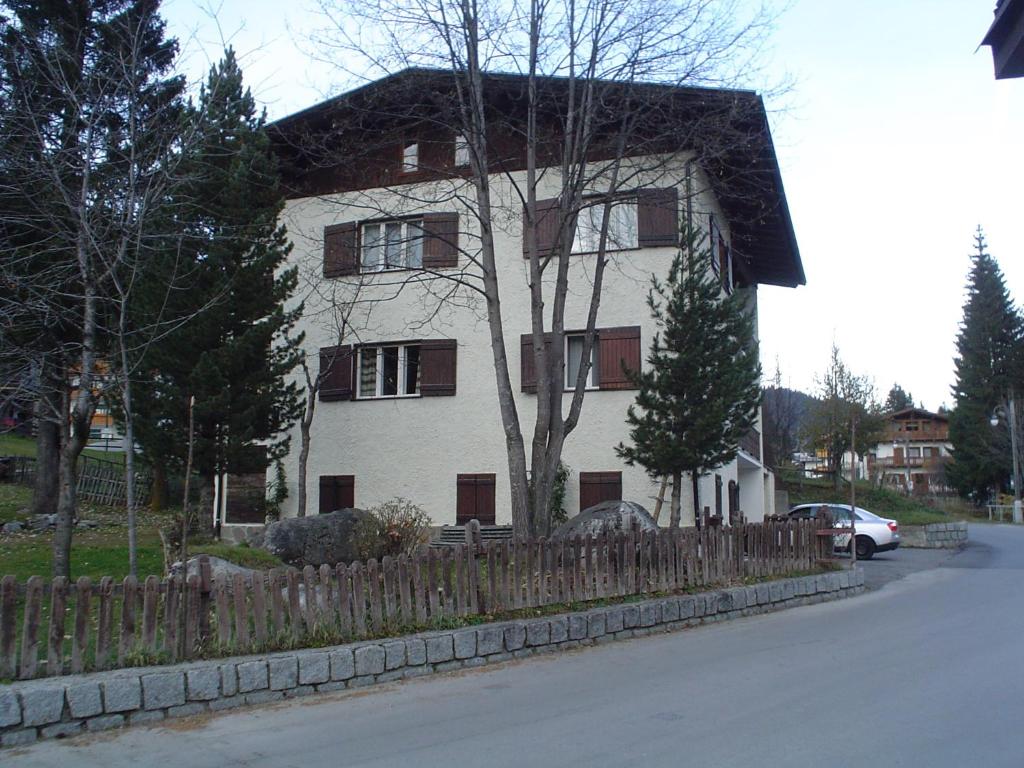 Biały dom z płotem przed nim w obiekcie Campiglio Quadrilocale Castelletto Inferiore w Madonna di Campiglio