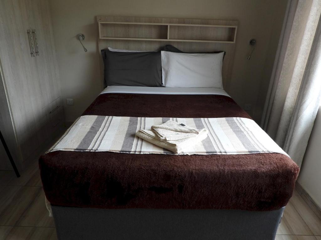 a bed in a small room with two towels on it at Executive apartment with 2 beds kitchenette - 2072 in Harare