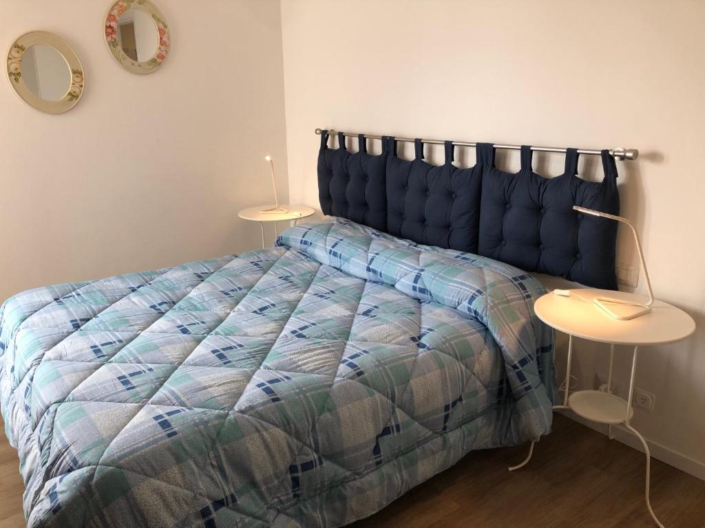 1 Schlafzimmer mit einem Bett mit blauer Decke und 2 Tischen in der Unterkunft MilanBed in Mailand