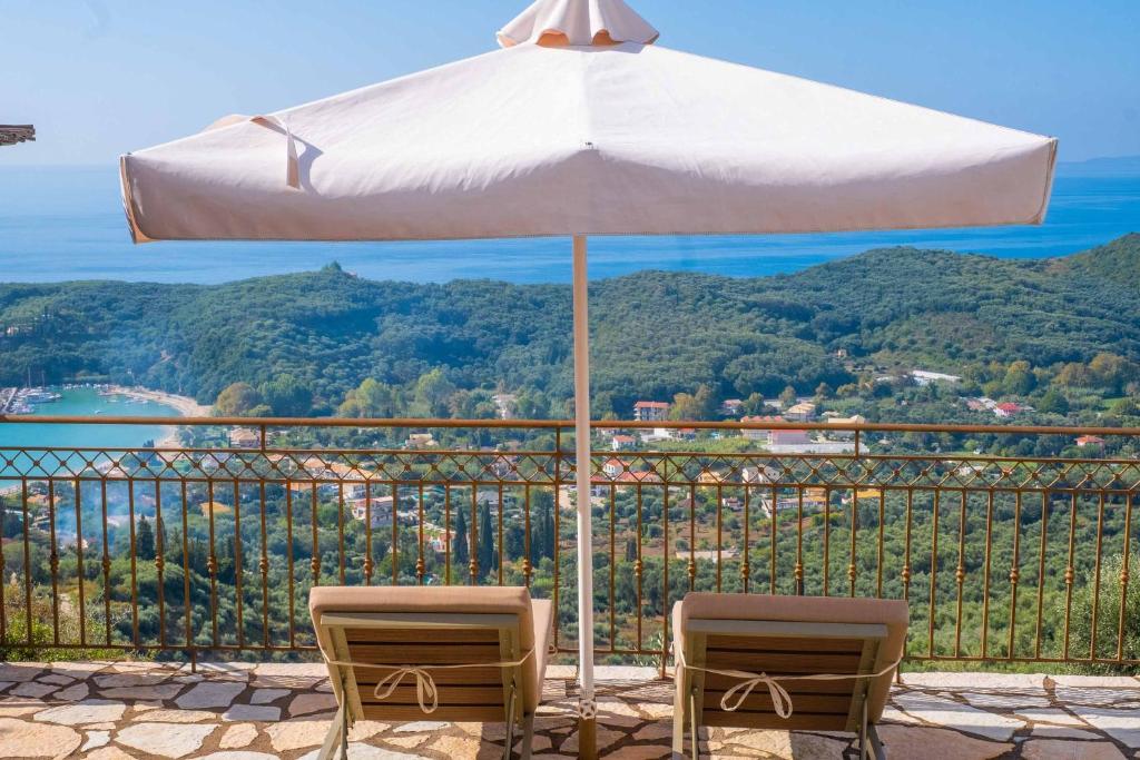 un paraguas blanco y 2 sillas en el balcón en Apolis Luxury Villa, en Agios Georgios