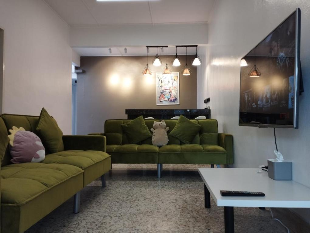 sala de estar con 2 sofás verdes y TV en Batu Pahat Taman Banang Homestay en Batu Pahat