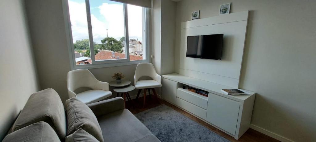 uma sala de estar com um sofá e uma televisão em Recanto Terraneo-Gramado em Gramado