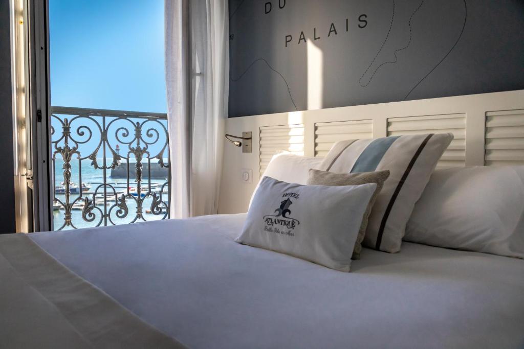 Una cama con sábanas blancas y almohadas en un dormitorio en Hotel Atlantique en Le Palais