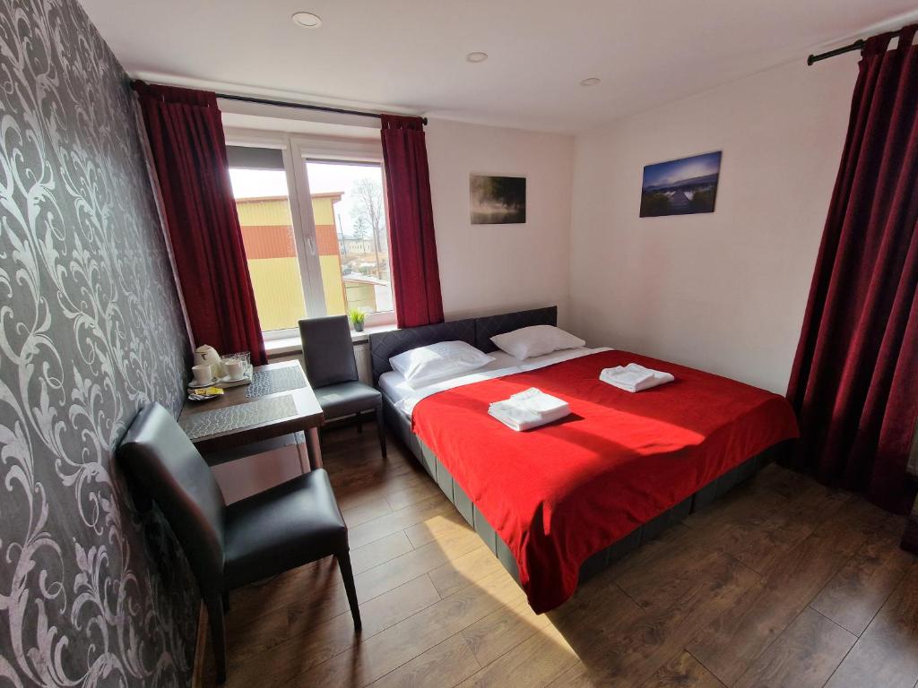 1 dormitorio con cama roja, mesa y sillas en KALIDA B&B Rooms for rent en Raseiniai