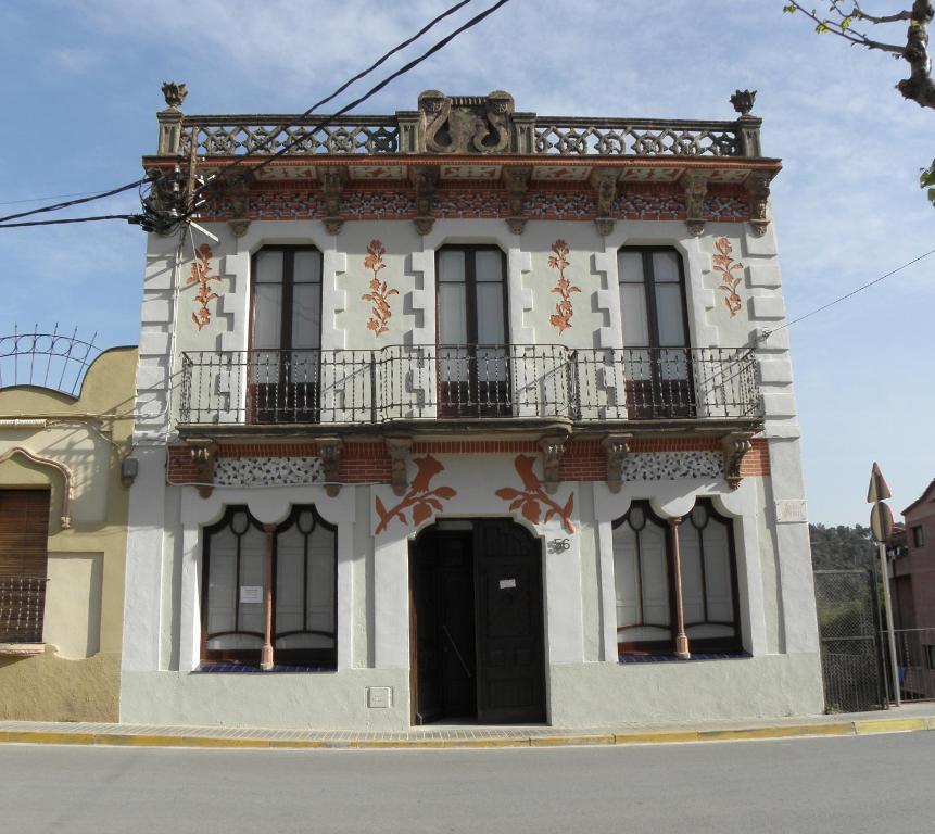 biały budynek z balkonem przy ulicy w obiekcie Hostal Cal Pla w mieście Sant Llorenc Savall