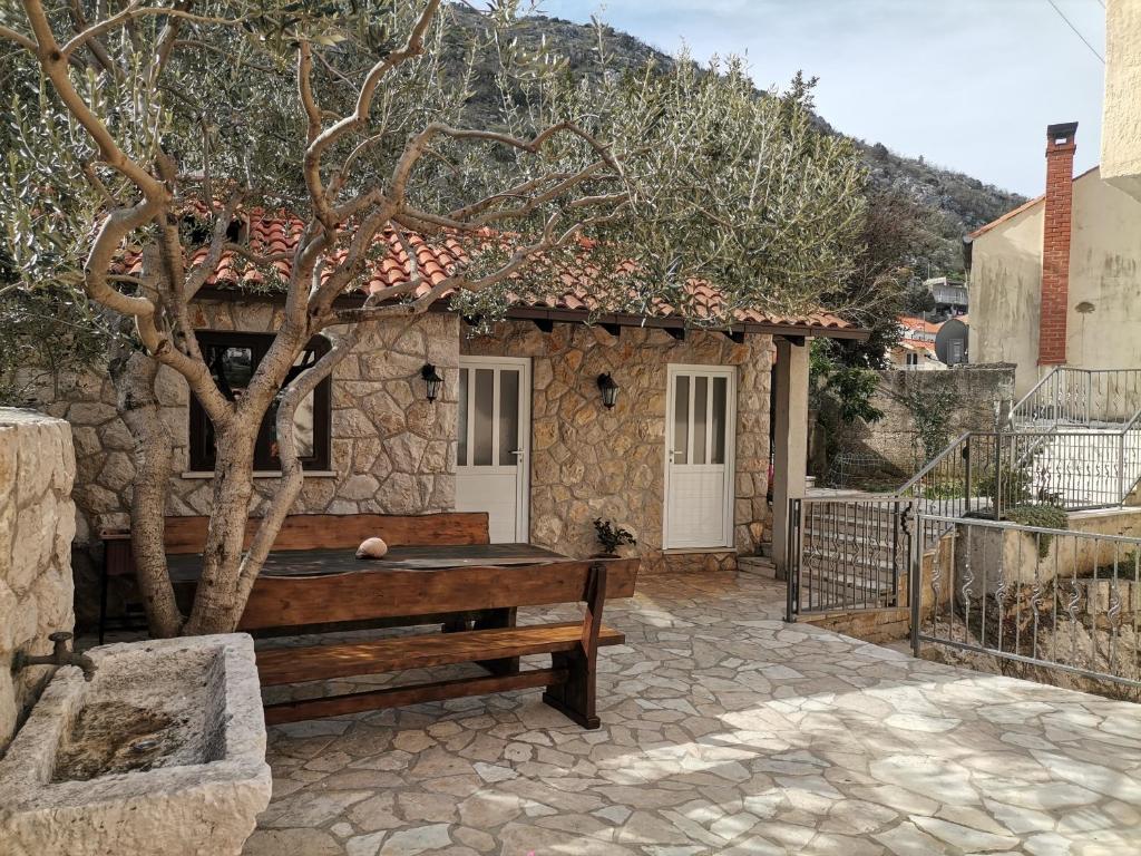 a stone house with a bench and a tree at Apartments and Rooms Maritimo in Dubrovnik