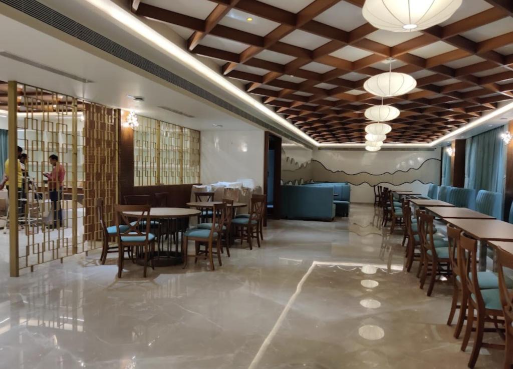 restauracja z drewnianymi sufitami, stołami i krzesłami w obiekcie Hotel Le Grandeur w mieście Narasimharaja Puram