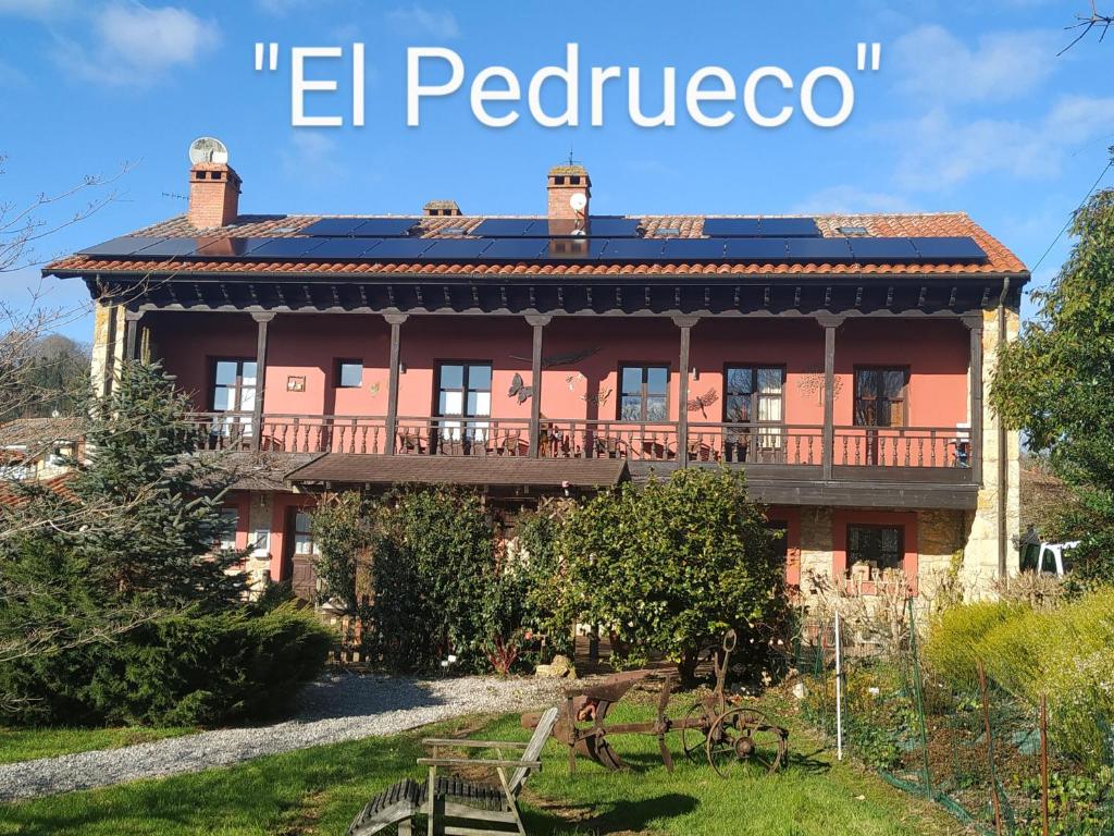 una gran casa roja con las palabras "el pueblo" en El Pedrueco turismo rural, en Nava