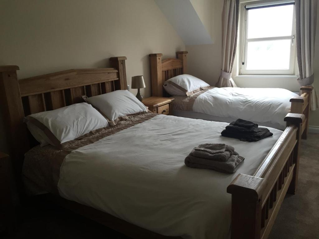 a bedroom with two beds with towels on them at Oatlands Self Catering Lets in Hillsborough