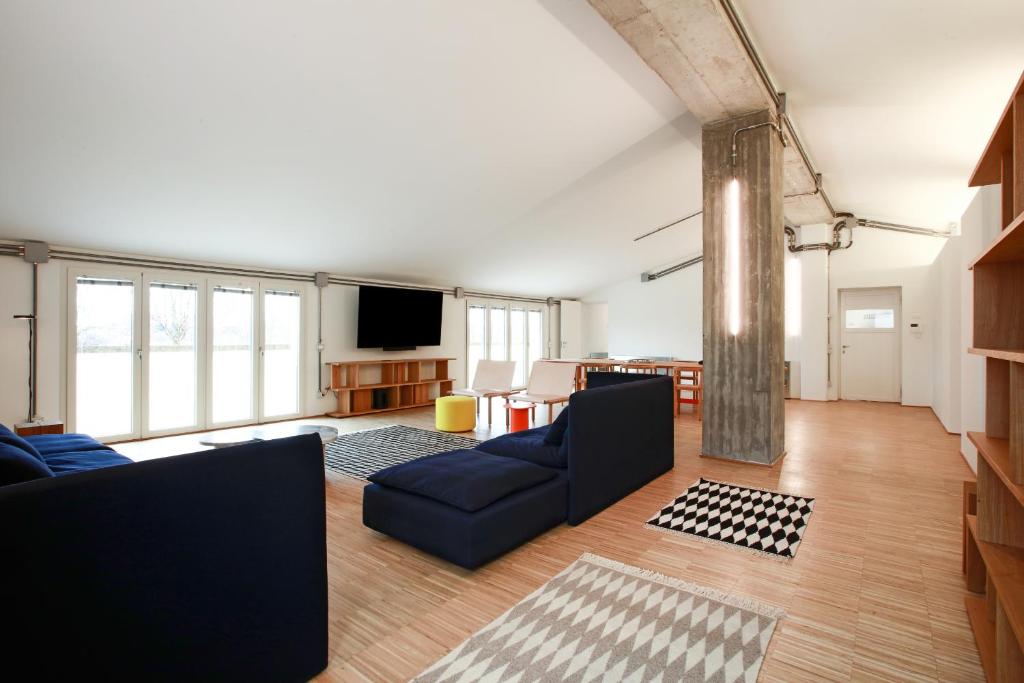 ein Wohnzimmer mit einem blauen Sofa und einem TV in der Unterkunft BasicVillage Milano in Mailand