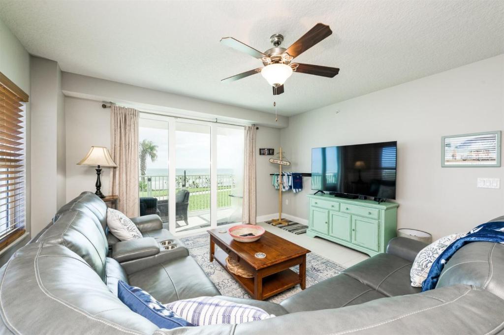 a living room with a couch and a flat screen tv at Unit 102 Aruba - 3 Bedroom Ocean Front in Daytona Beach