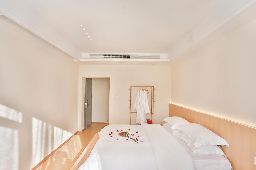 a white room with a bed with flowers on it at Flower Whisperer Homestay Tianmenshan Store free airport and station pick-up in Zhangjiajie