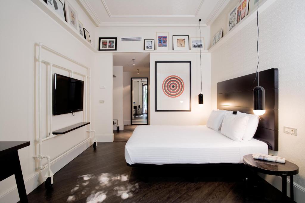 a white bedroom with a bed and a television at Praktik Garden in Barcelona