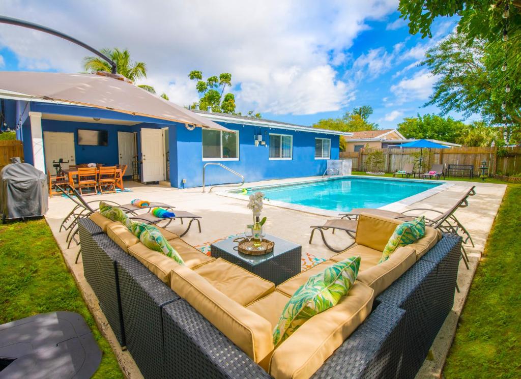 um quintal com um sofá e uma piscina em Cozy Blue house blocks from beach with Private Pool, BBQ, Backyard em Deerfield Beach