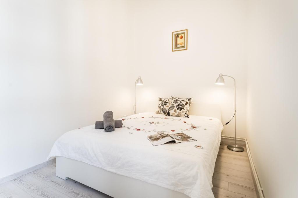 ブダペストにあるCorbie Downtown Apartmentの白いベッドルーム(ランプ付きの白いベッド付)