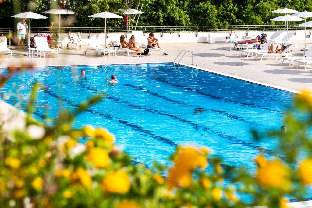 una piscina con persone sedute a sdraio e ombrelloni di Hotel Villa Pamphili Roma a Roma