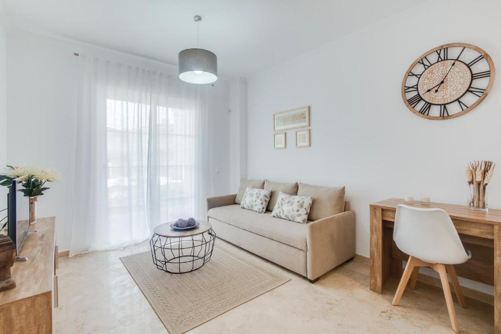 a living room with a couch and a clock on the wall at Apartamento Small Oasis Manilva in Manilva