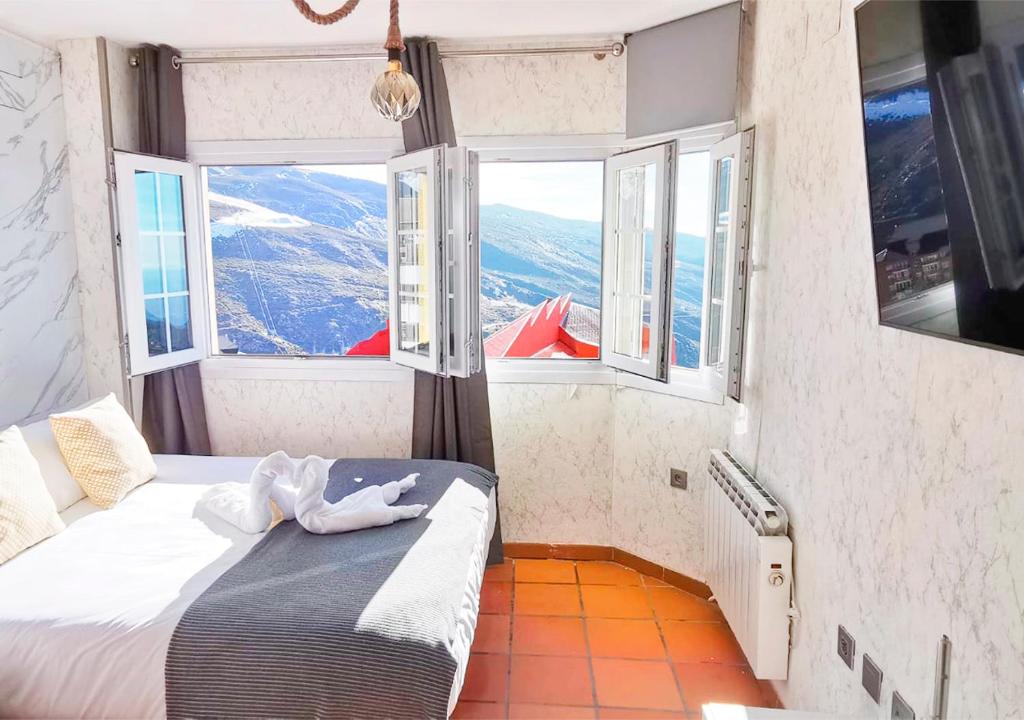 - une chambre avec un lit et des fenêtres offrant une vue dans l'établissement Estudio con vistas a Sierra Nevada en Edificio Arttyfal by ISA Hoteles, à Monachil