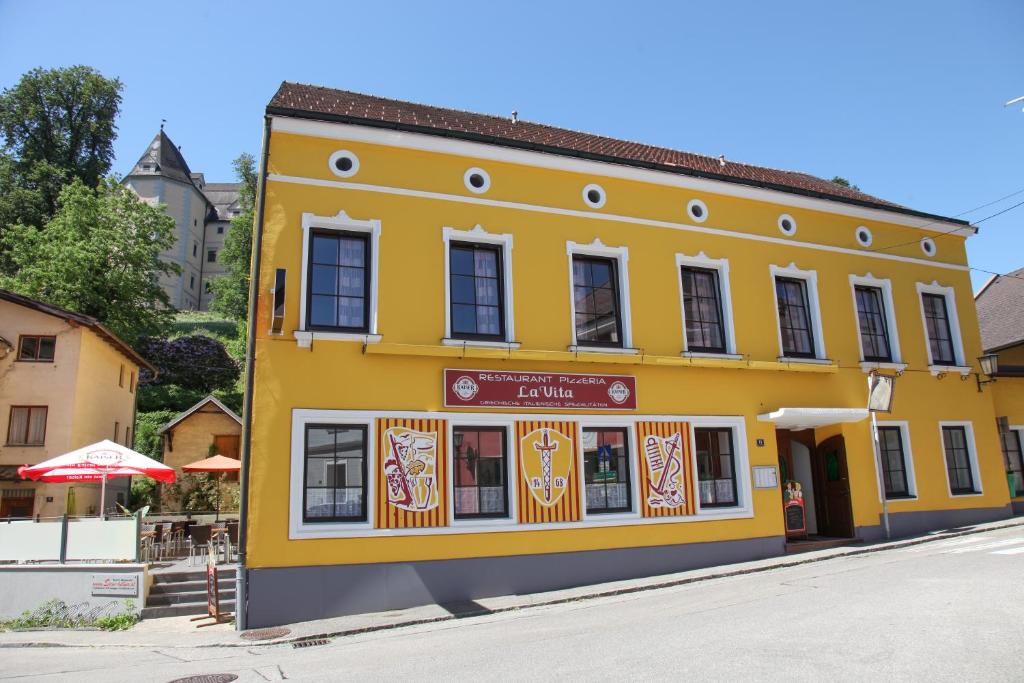 ein gelbes Gebäude an der Straßenseite in der Unterkunft Pension Stadt Grein in Grein