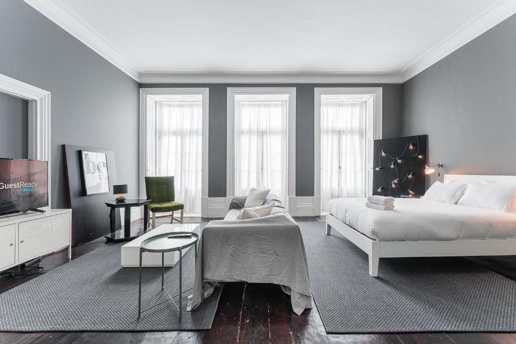 Un dormitorio con una cama, un sofá y un televisor. en GuestReady - Innvict Residences, en Oporto