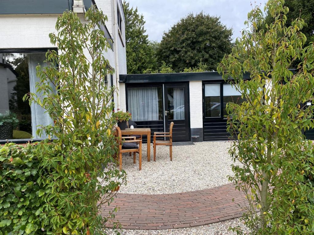 une terrasse avec une table et des chaises devant une maison dans l'établissement 't Achterhuis (2 persons), à Otterlo