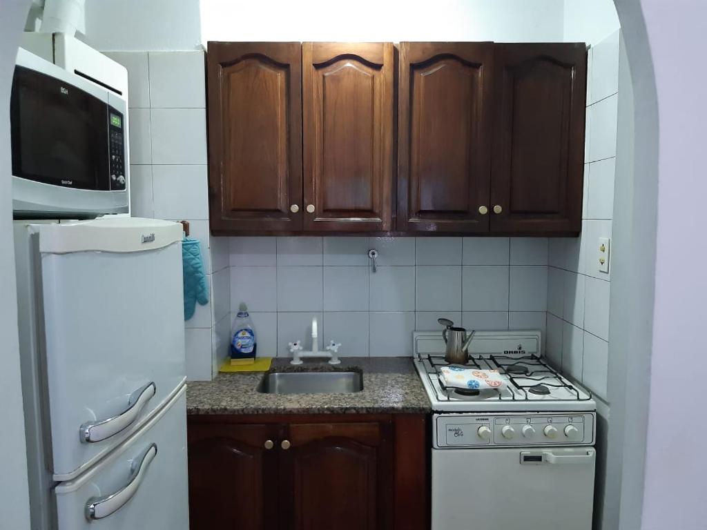 cocina con armarios de madera, fogones y fregadero en Departamento Centro en San Salvador de Jujuy