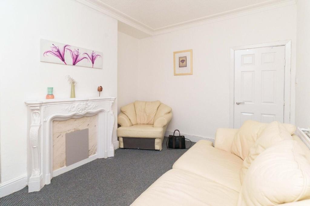 a living room with a white fireplace and a white couch at Dent House Stays in Hunslet