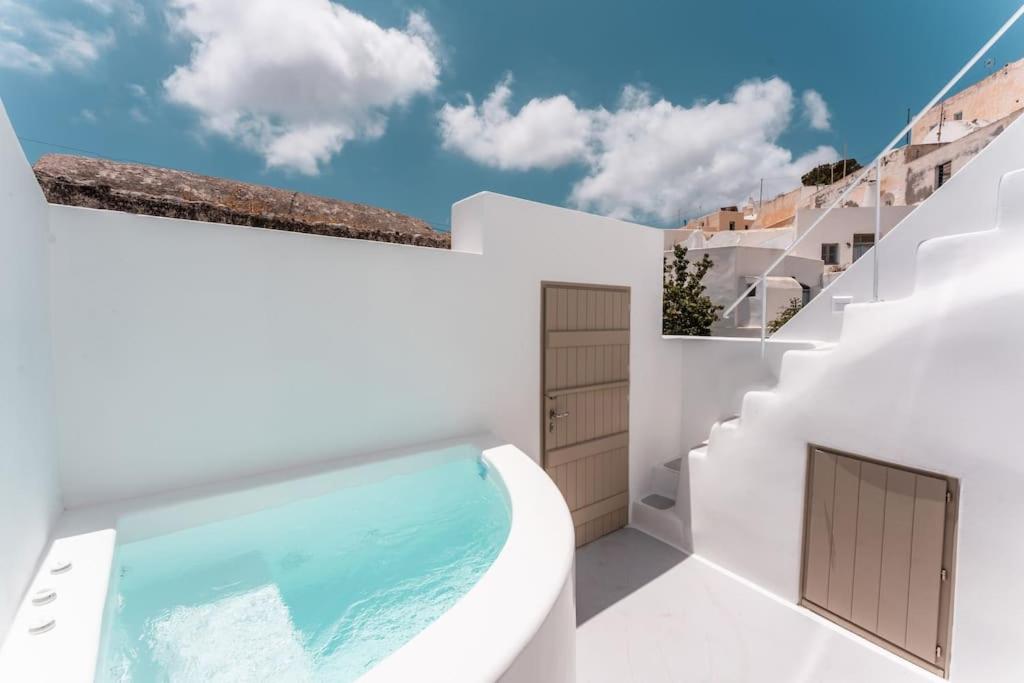 a white house with a swimming pool and stairs at AKRI santorini with heated jacuzzi in Emporio