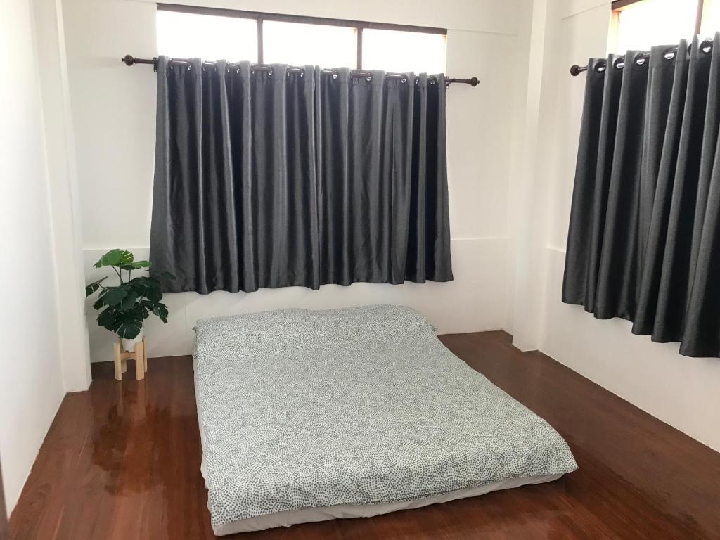 a bedroom with black curtains and a mattress on a wooden floor at บ้านสุขใจ (Ban Suk Jai) 