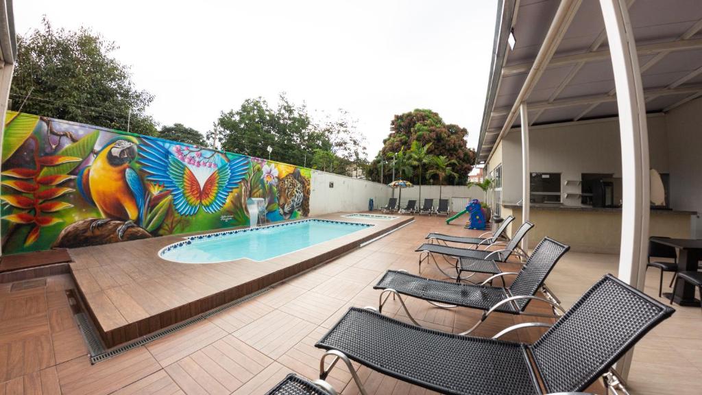 a pool with chairs and a wall with a mural at Allegro Hotel in Goiânia