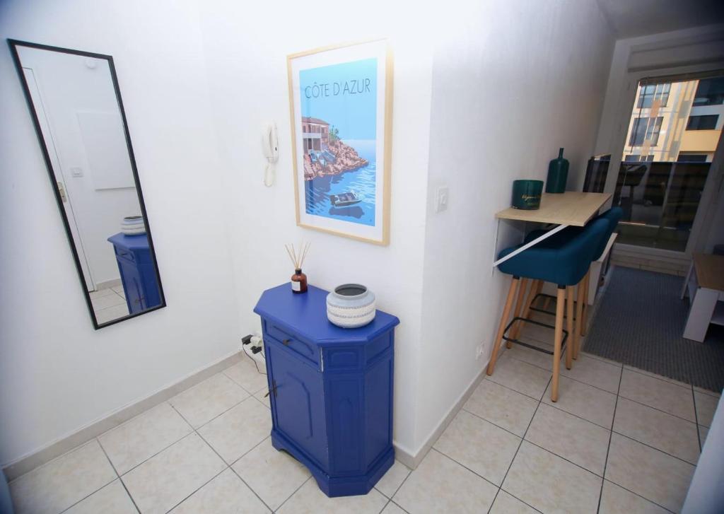 een kamer met een blauwe tafel en een spiegel bij Charmant studio avec terrasse, refait à neuf in Aix-en-Provence